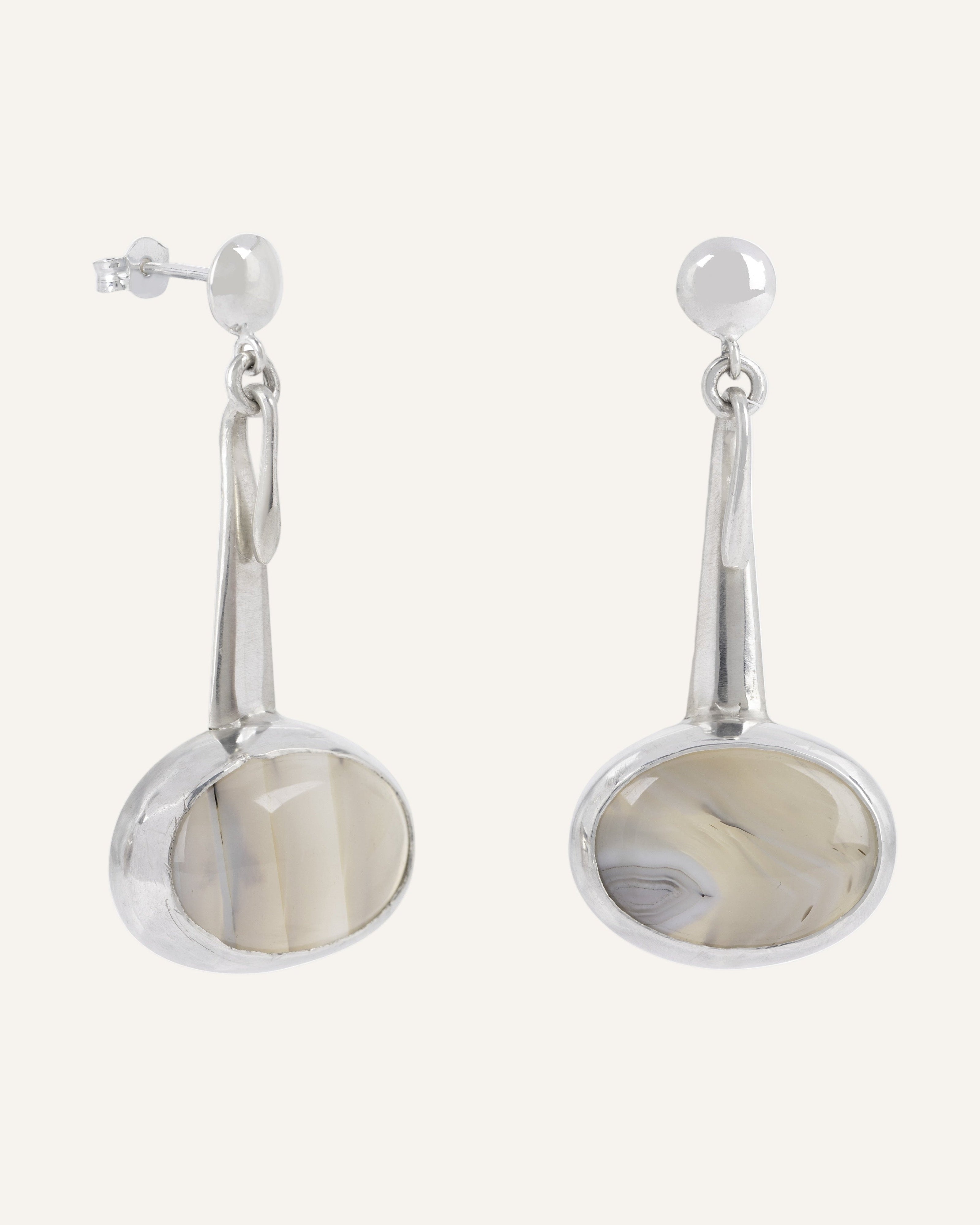 Pair of silver drop earrings with oval grey agate on a white background